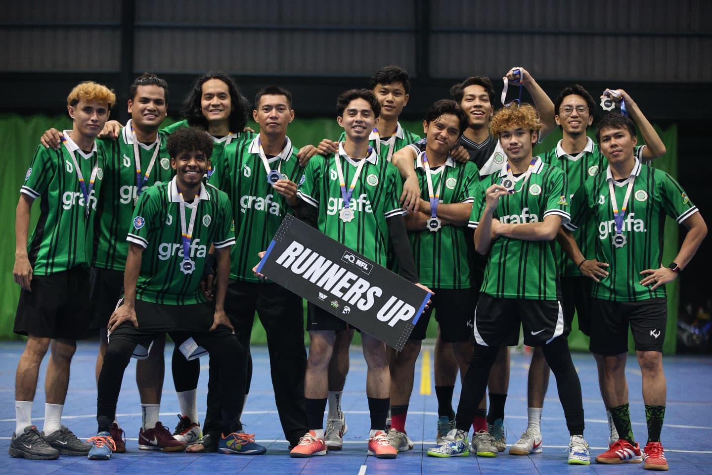 The Petaling Jaya Juara squad in green kits, wearing medals and holding a Runners Up banner